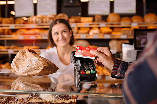 sammeln_teaser Bezahlsituation in Bäckerei. Im Fokus: Hand hält Sparkassen Card an Kartenlesegerät.
